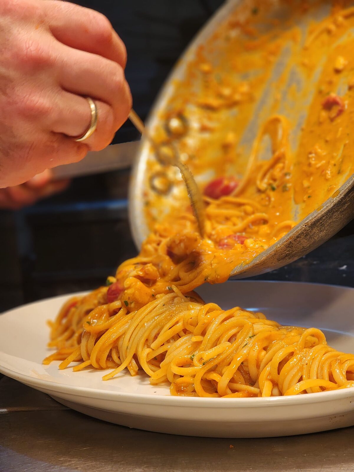 Fresh spaghetti being plated from the pan