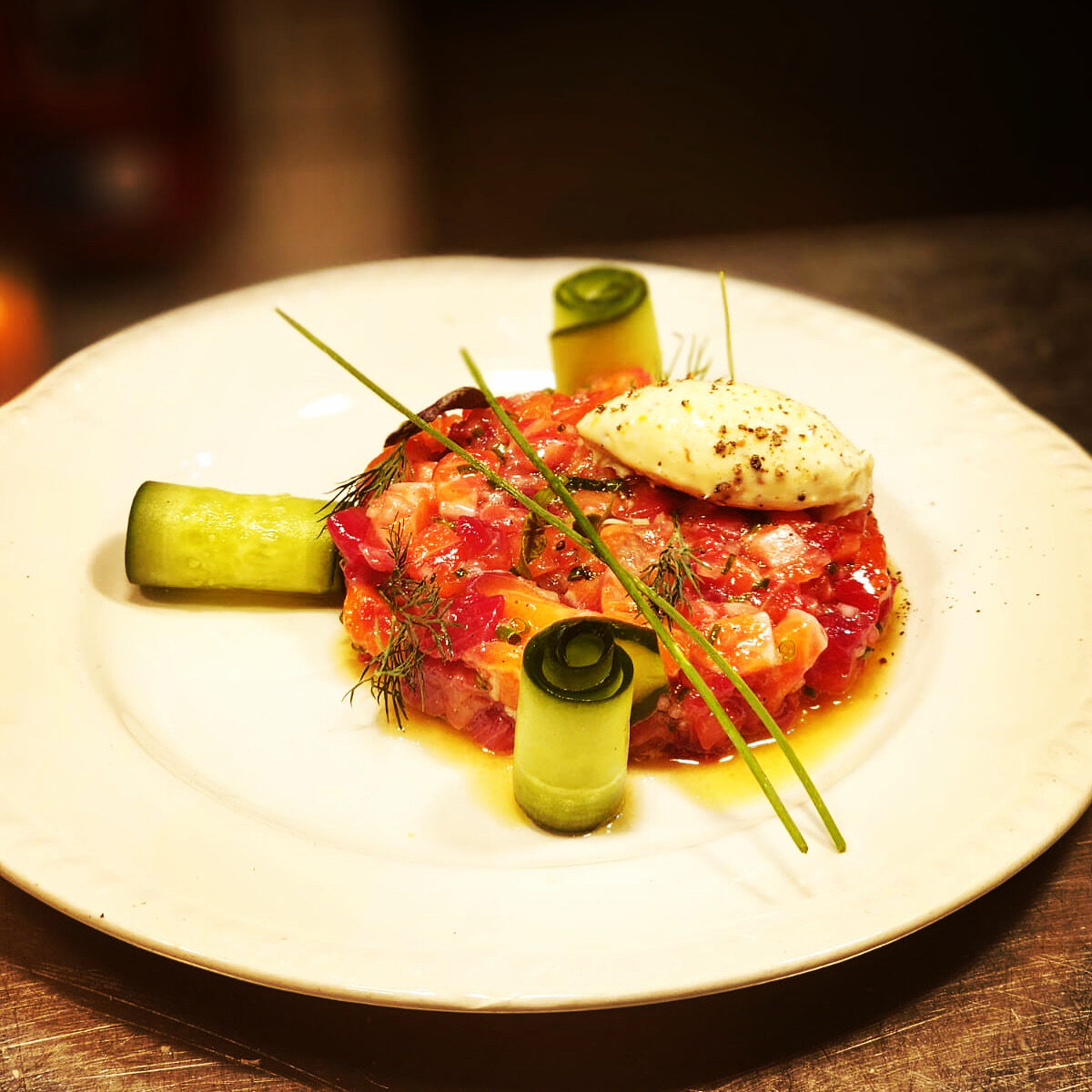 A precisely plated tartare with cucumber and herbs